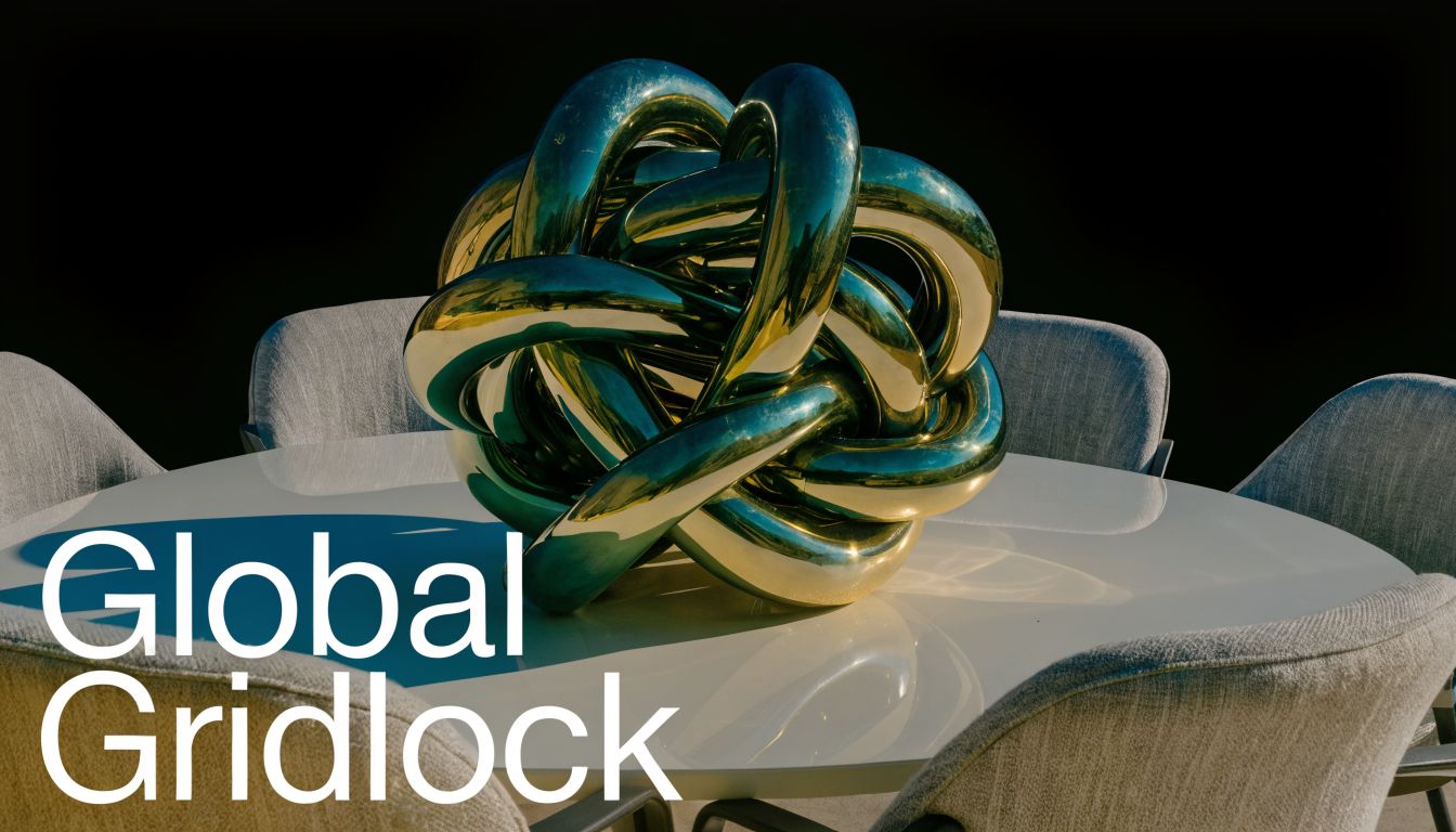 A large metallic abstract sculpture sitting on a white circular table surrounded by several grey chairs.